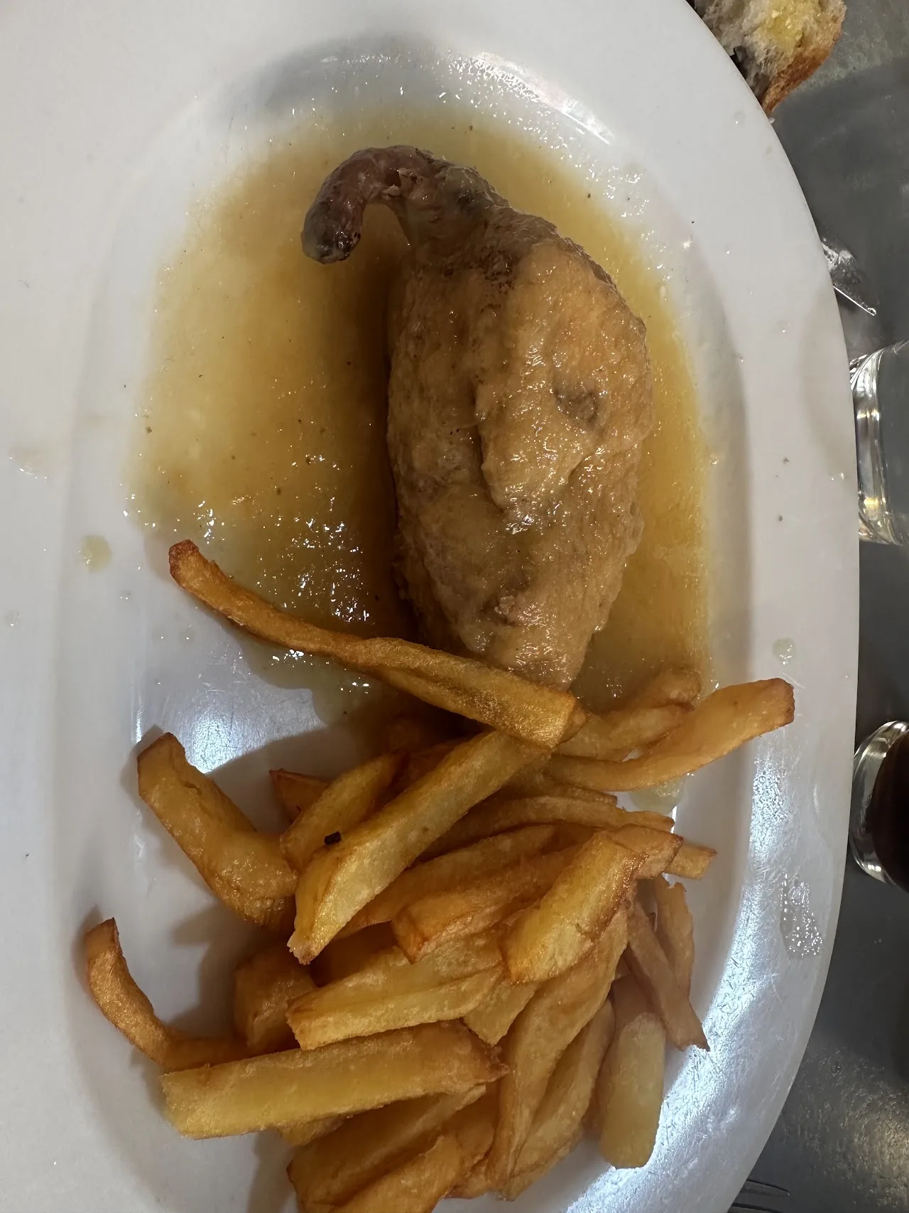 A roasted chicken leg with french fries in sauce