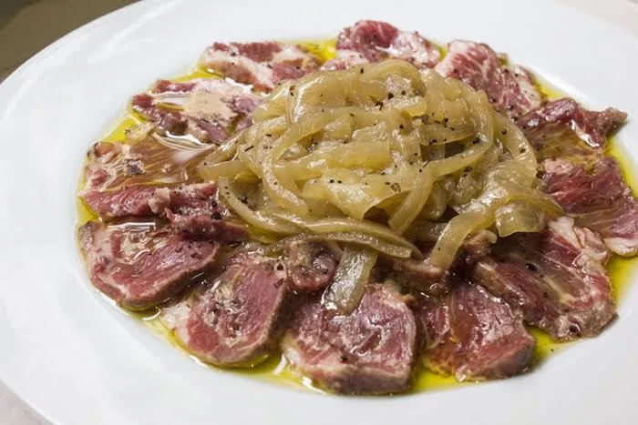 Thinly sliced beef topped with pickled onions and olive oil