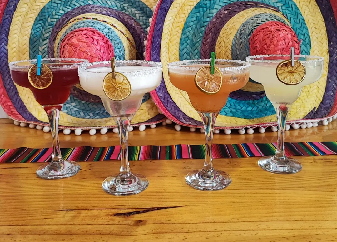 Four margaritas in different flavours lined up on a wooden bar