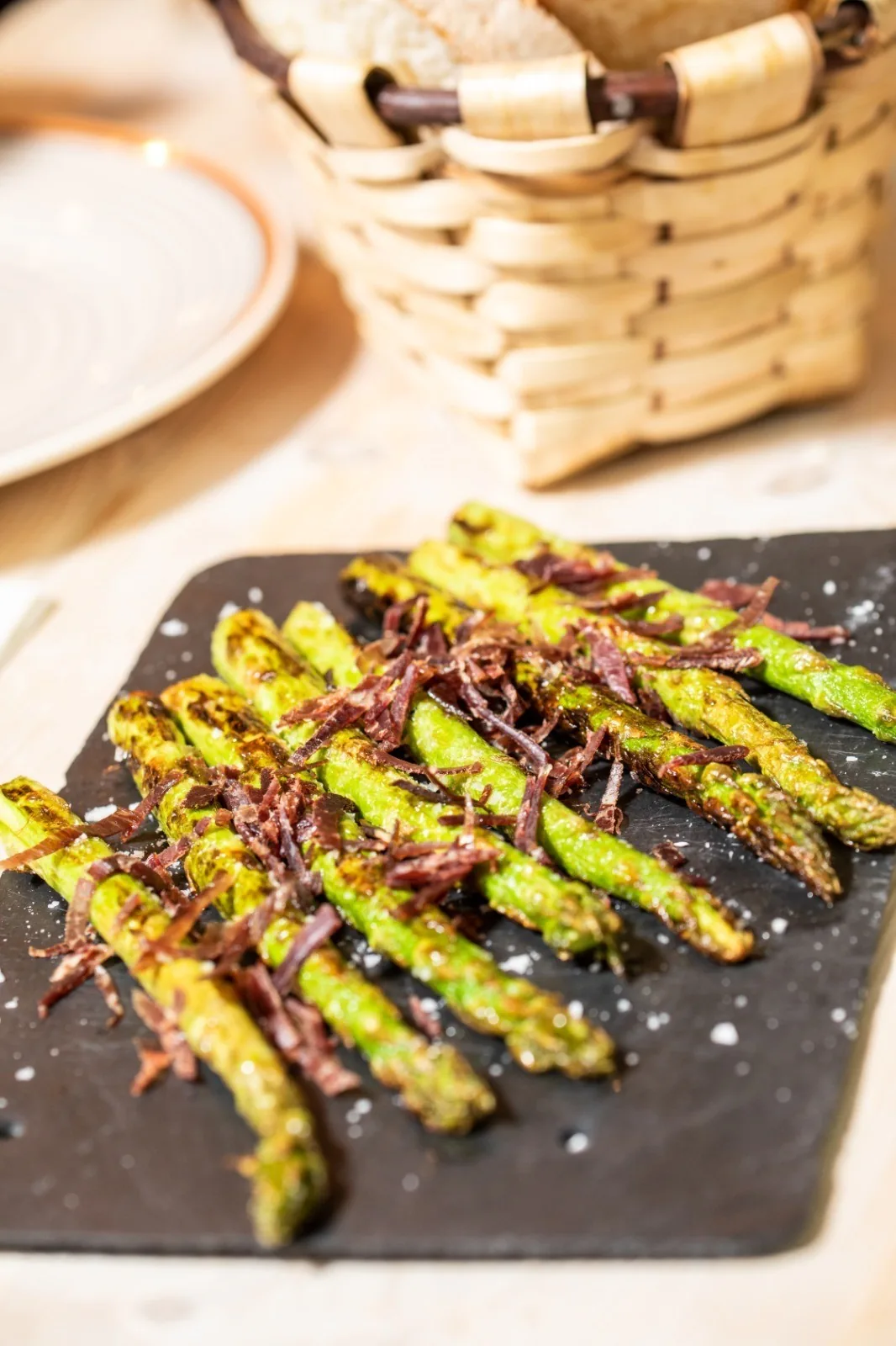 Grilled asparagus spears with dark flakes on a slate board