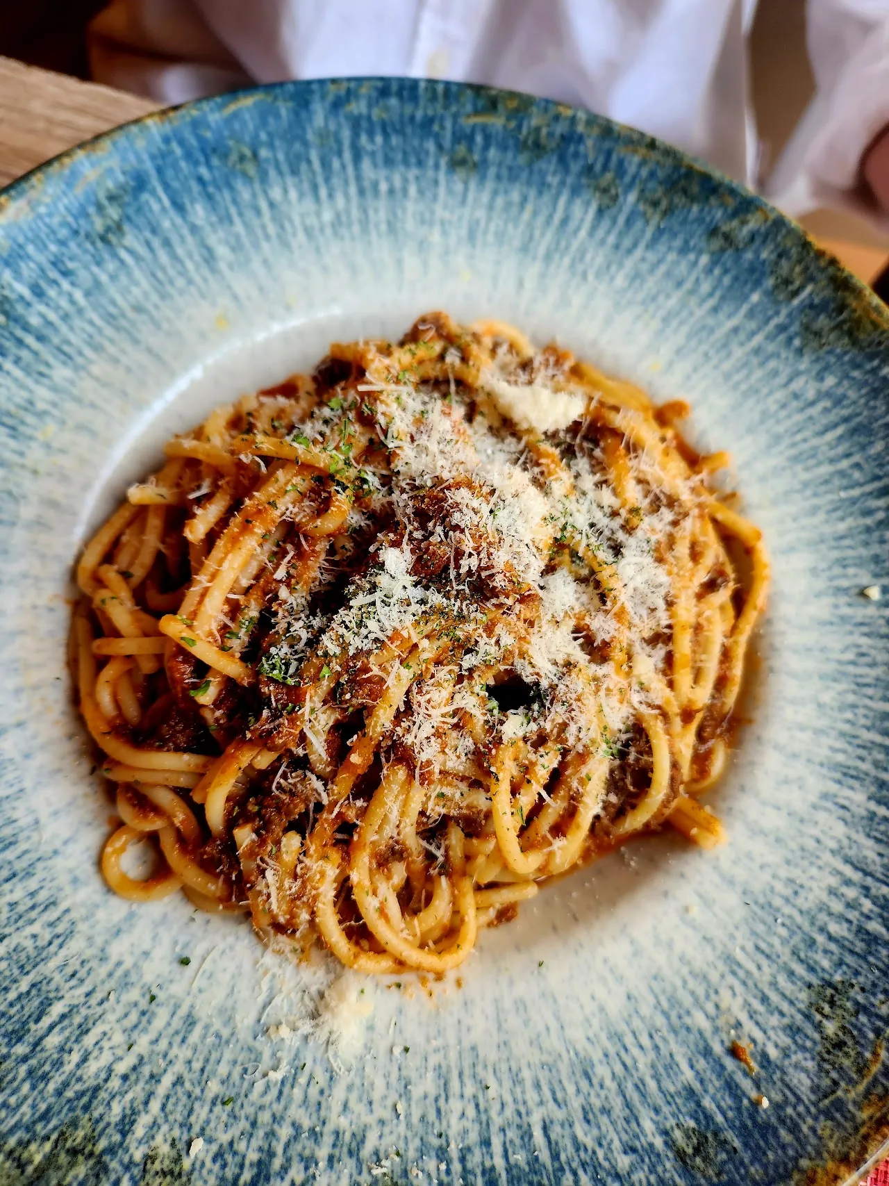 A plate of spaghetti in tomato sauce topped with basil and grated cheese