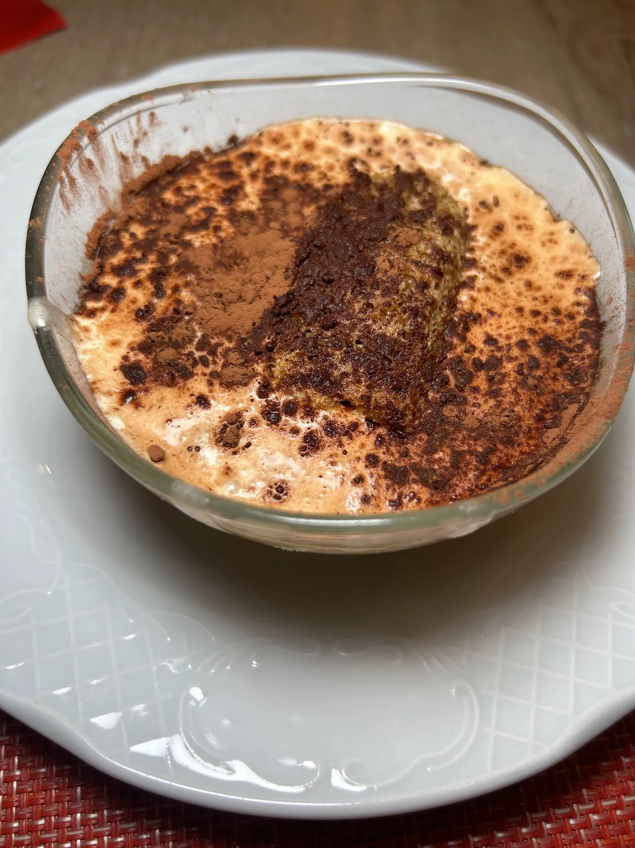 A tiramisu dusted with cocoa powder in a glass dish