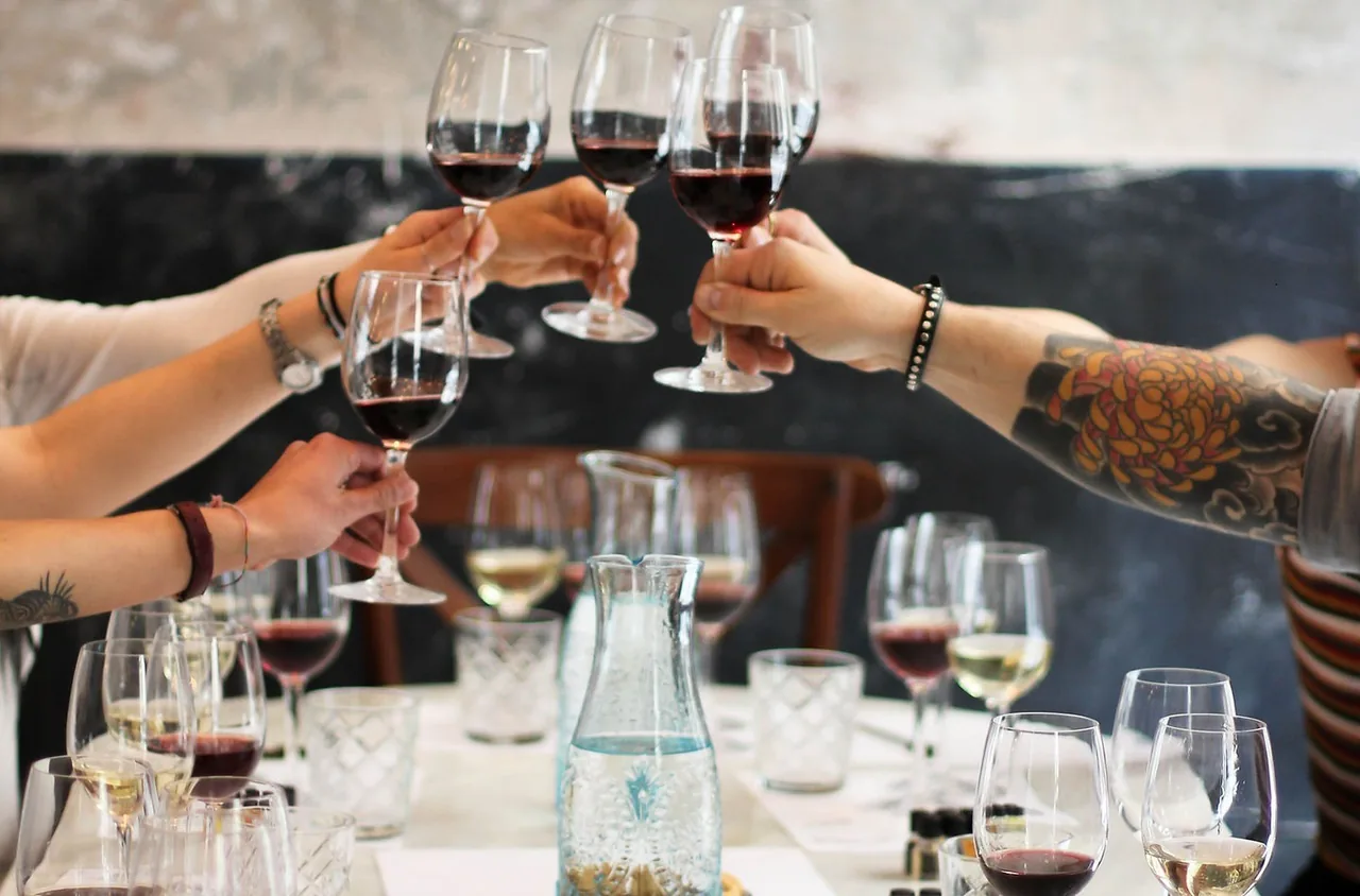 Hands raising glasses of red wine in a toast over a table