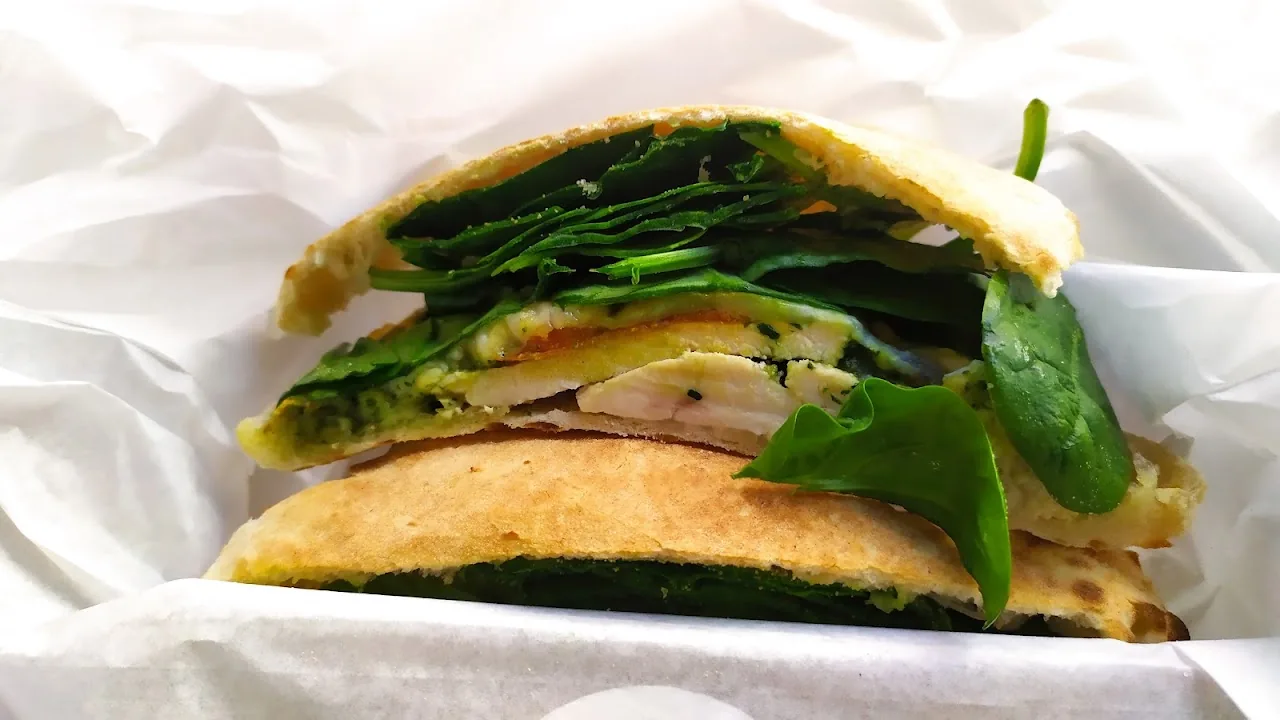 A stuffed flatbread sandwich filled with leafy greens