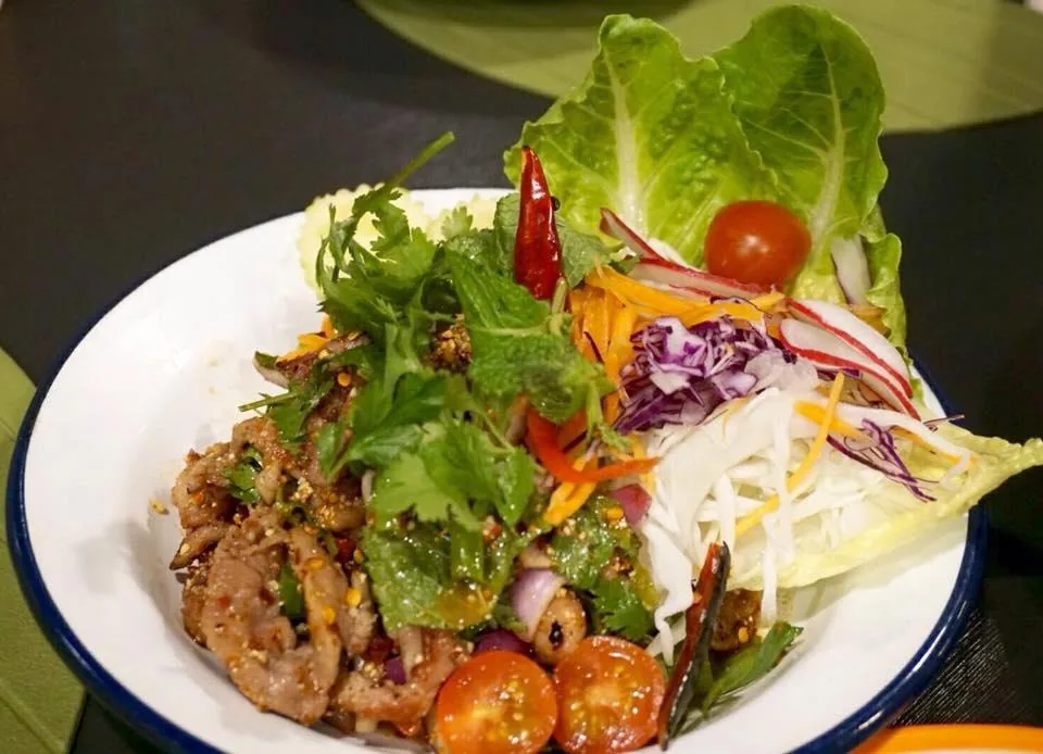 A Thai salad with mixed greens, herbs, cherry tomatoes and shredded vegetables
