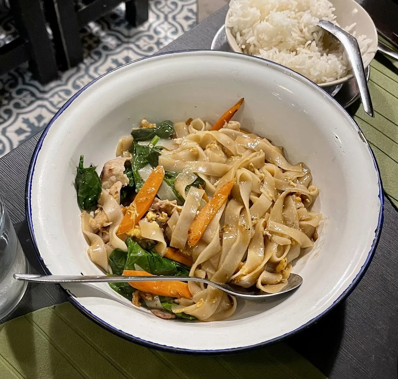A bowl of stir-fried rice noodles with vegetables and herbs