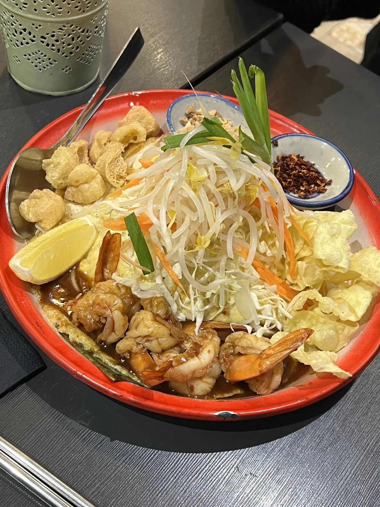 A plate of pad thai with shrimp, bean sprouts, crushed peanuts and a lime wedge