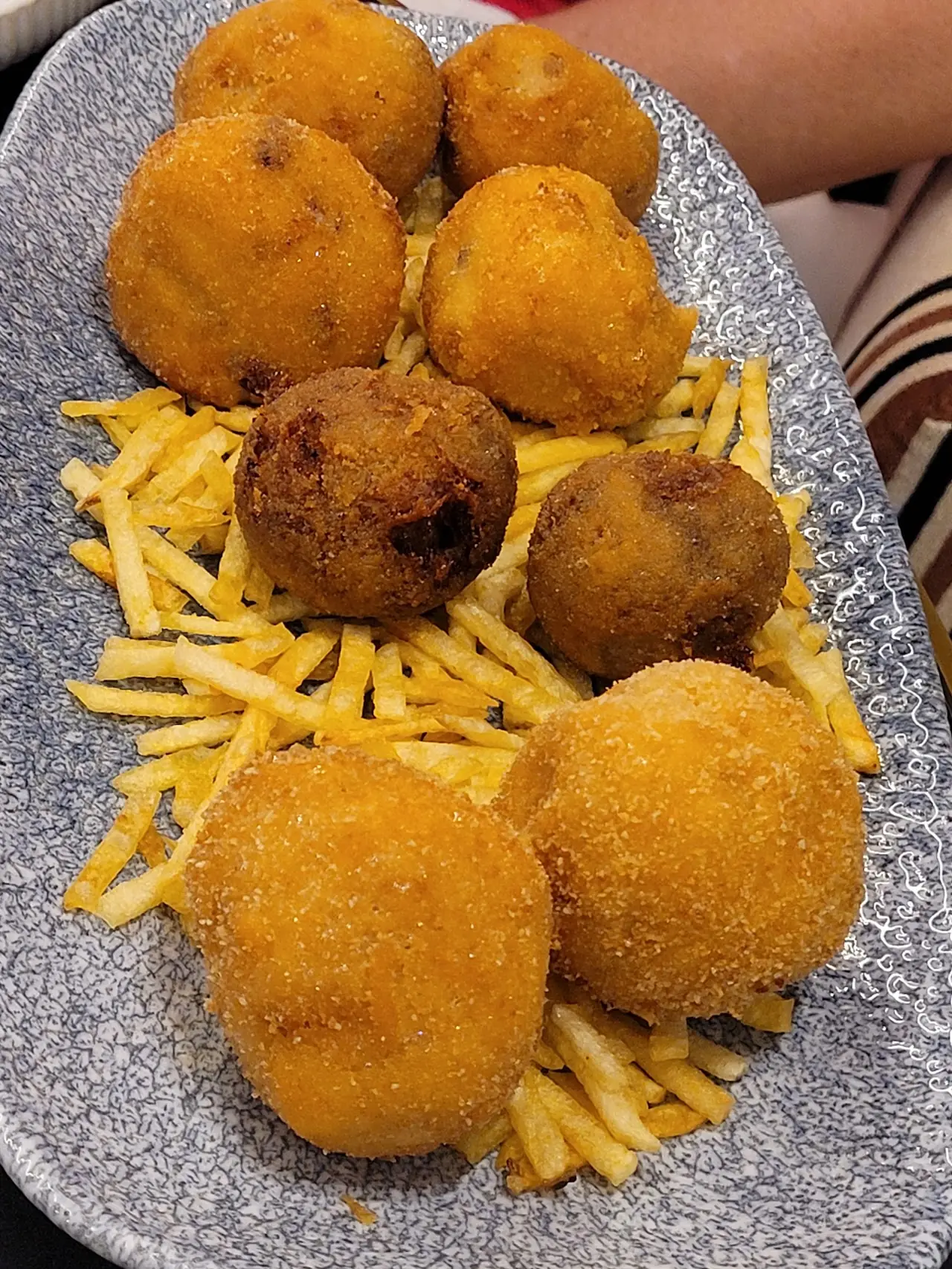 Breaded croquettes plated with a side of shoestring fries.