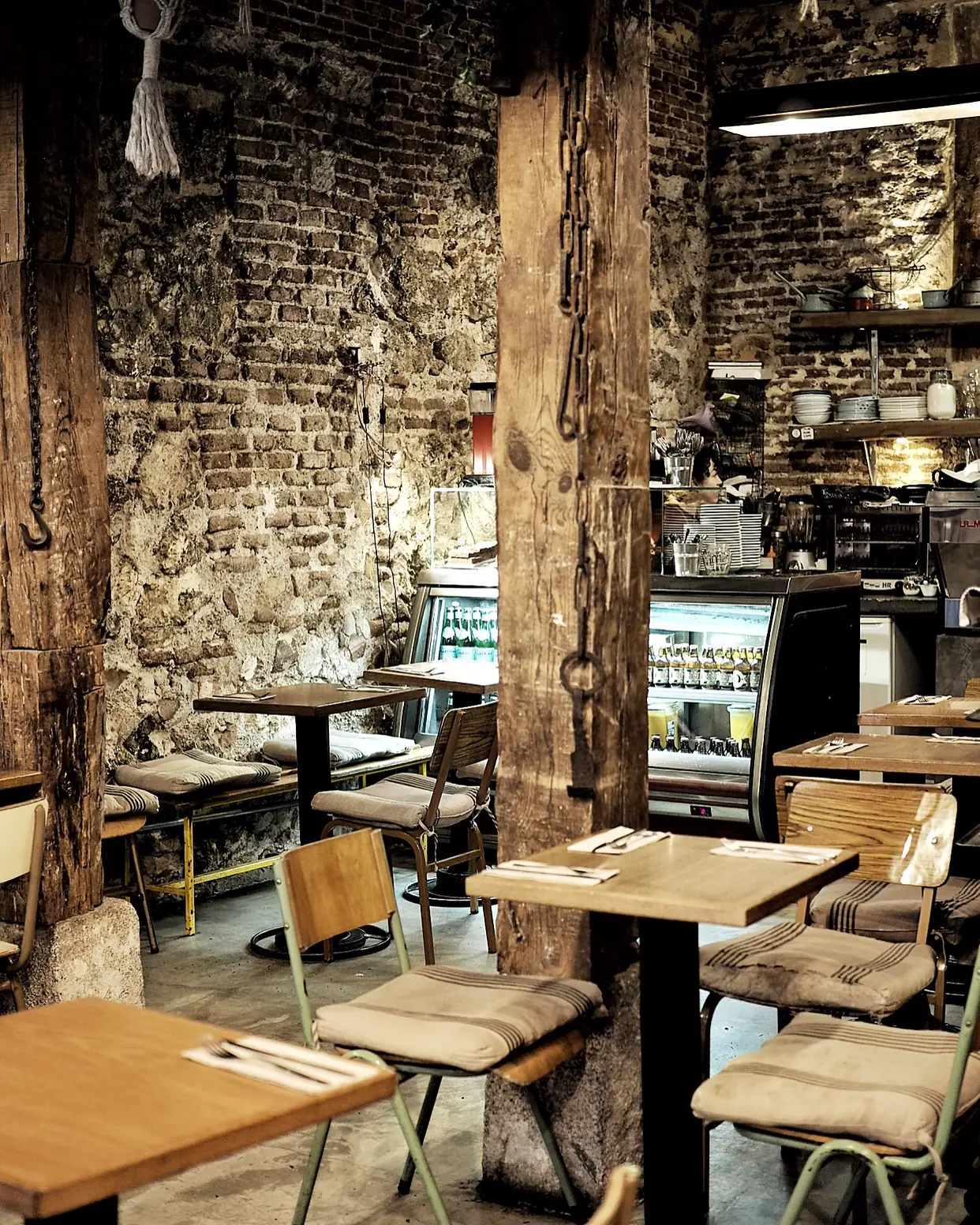 The cafe's exposed-brick dining room with wooden tables, cushioned chairs, and a pastry counter