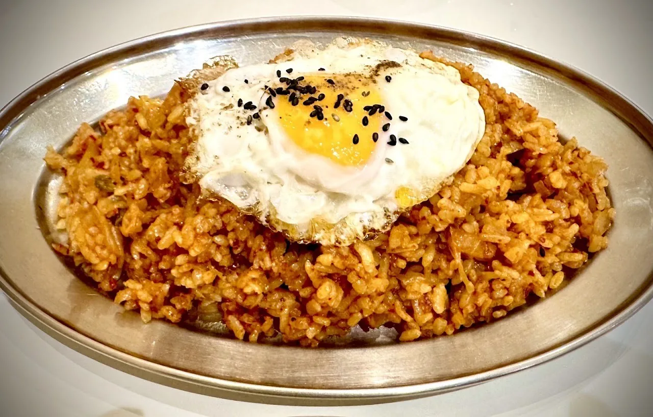 Fried rice topped with a fried egg on a metal tray