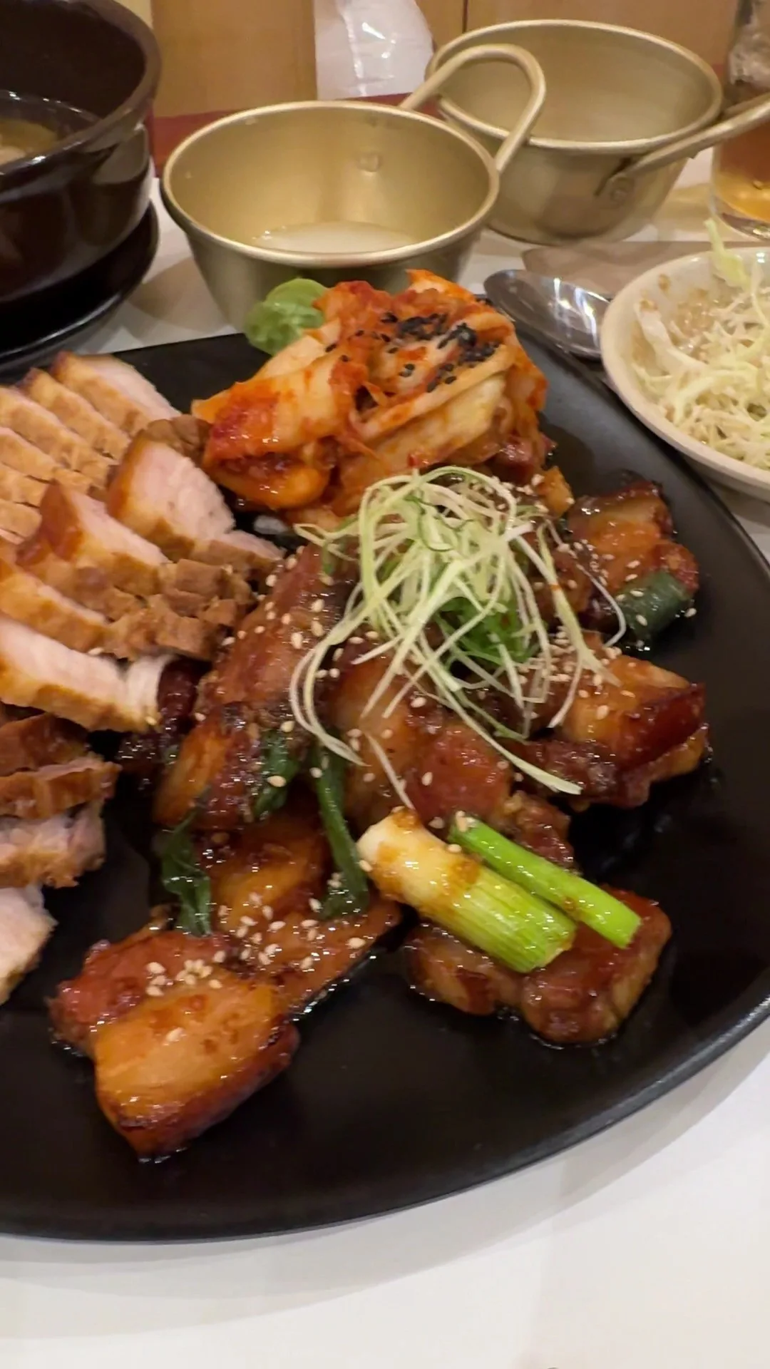 Sliced pork with spring onion on a dark plate