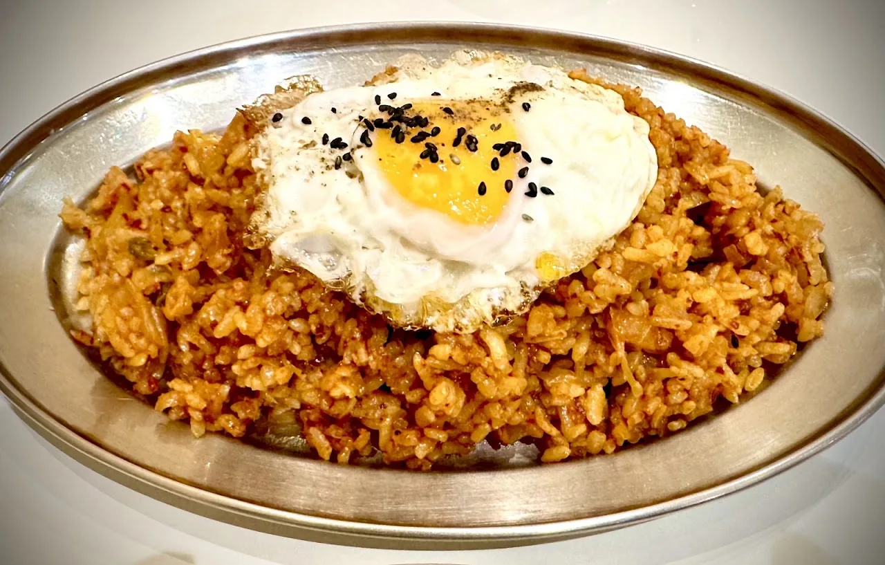 A plate of fried rice topped with a fried egg and sesame seeds
