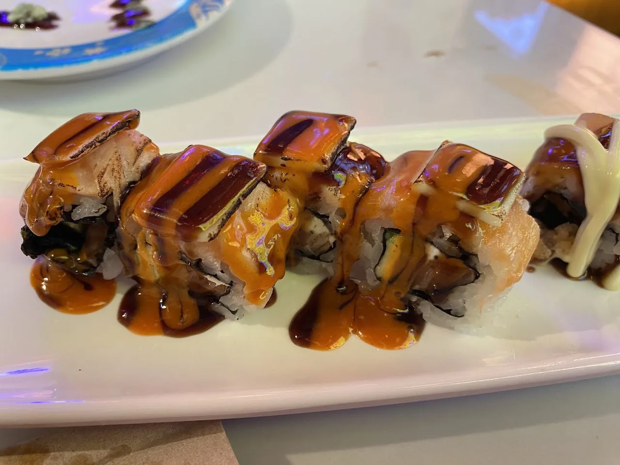 Sushi rolls drizzled with sauce on a white plate