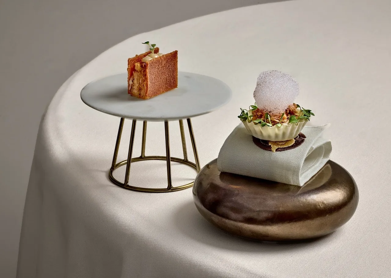 Small plated bites on stands and a dark stone on a round table with a white cloth