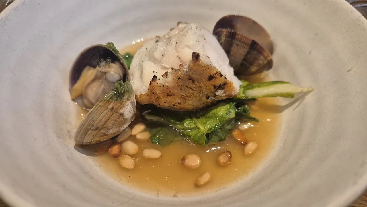 A pale plate of clams, cream and beans in a light broth