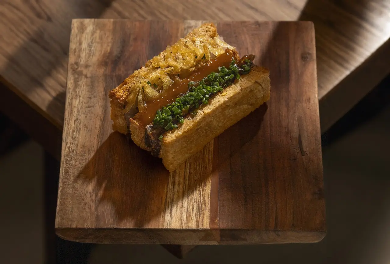 Toasted sandwich with crispy fried onions, chives and a savory glaze on a wooden board