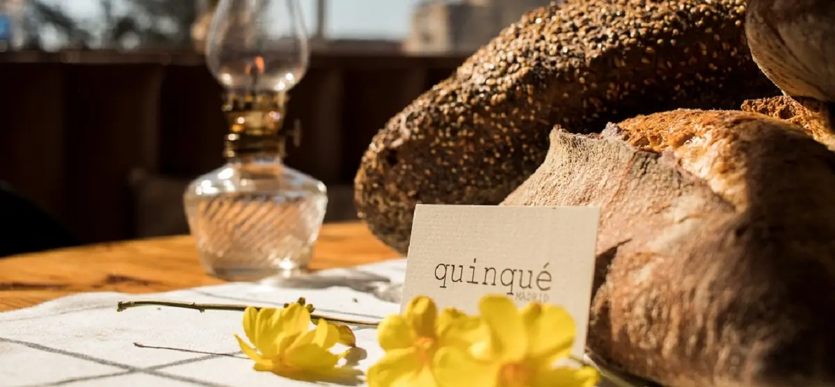 Crusty artisan bread loaves on a table beside a Quinqué place card