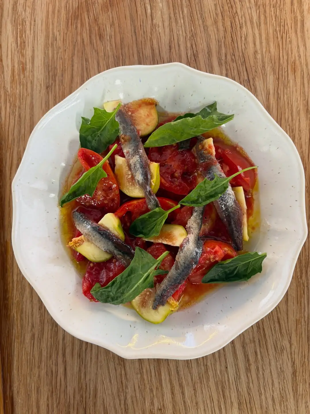 Salad of anchovies, tomato, fig and basil in olive oil