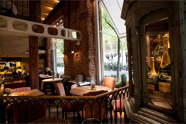 Interior seating area with a table by a window and a glass cabinet holding champagne bottles.