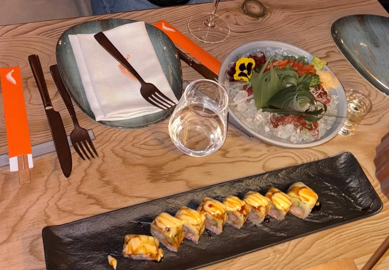 Sushi rolls arranged on a black plate with an edible flower garnish