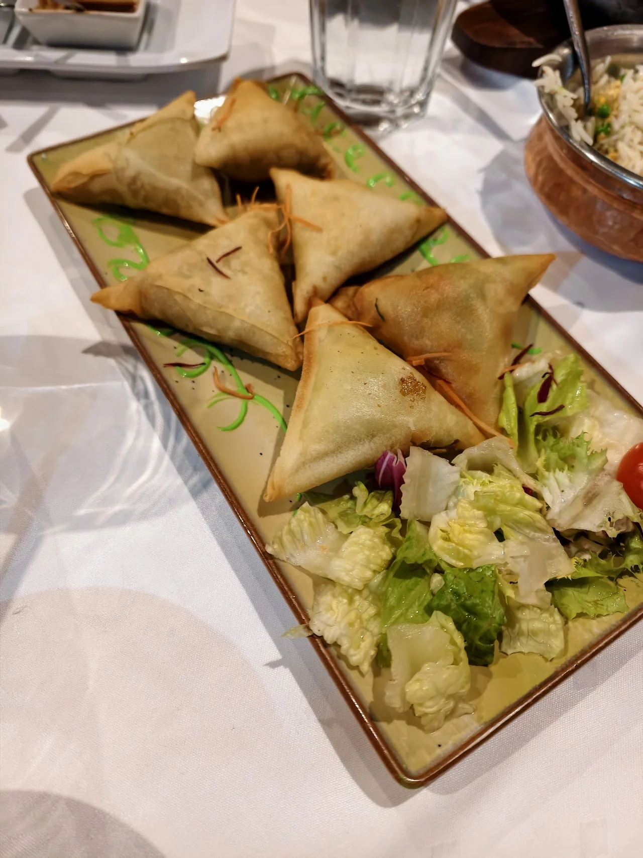 A platter of golden fried samosas with a side salad