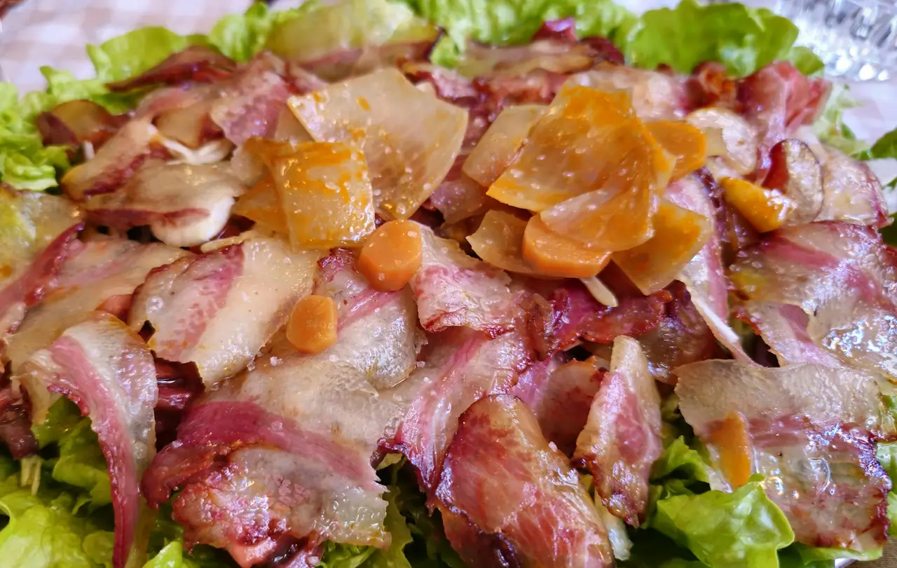 Plate of sliced octopus with pickled carrot and turnip over lettuce