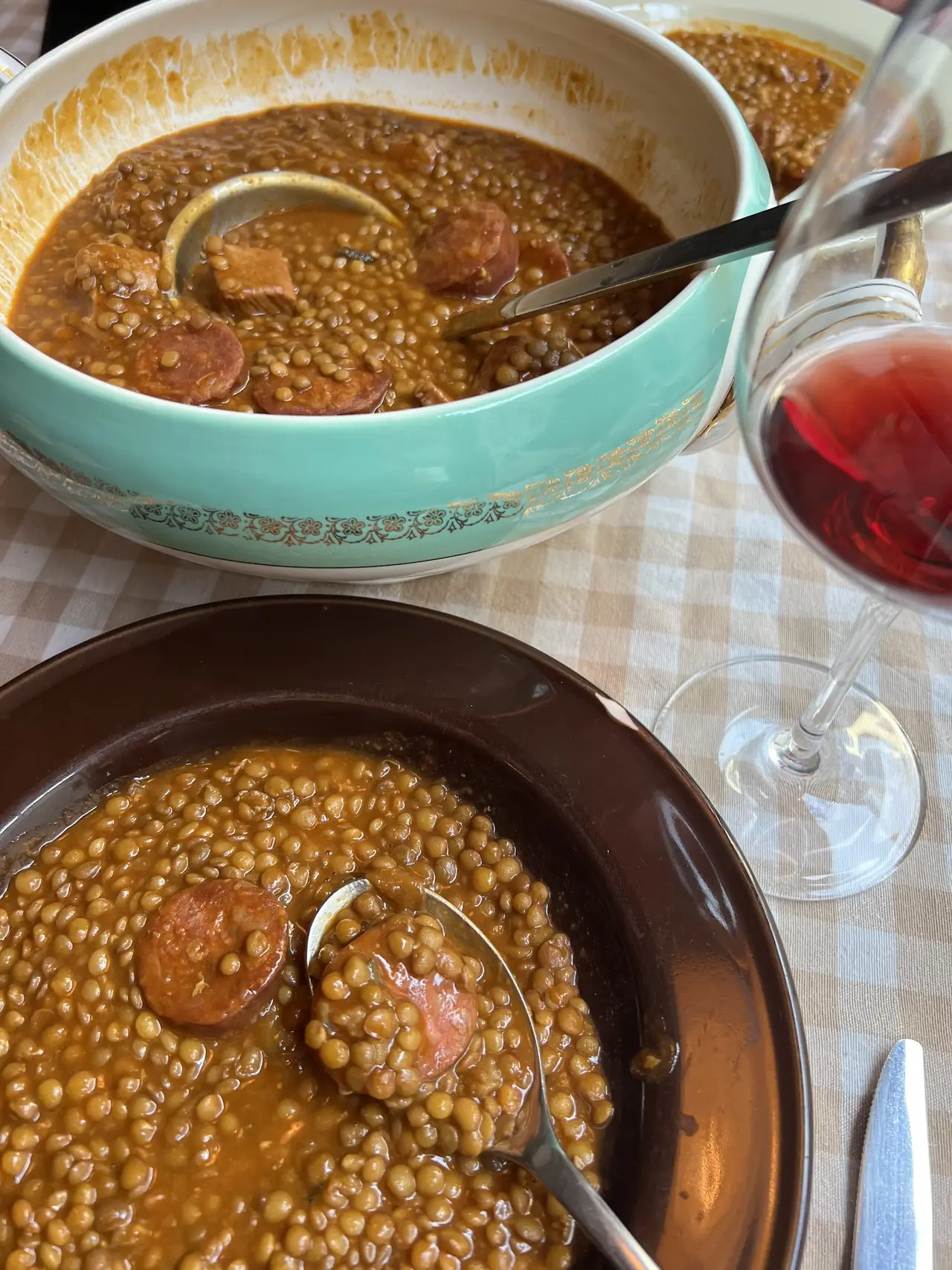 Bowls of lentil stew with chorizo, served alongside red wine