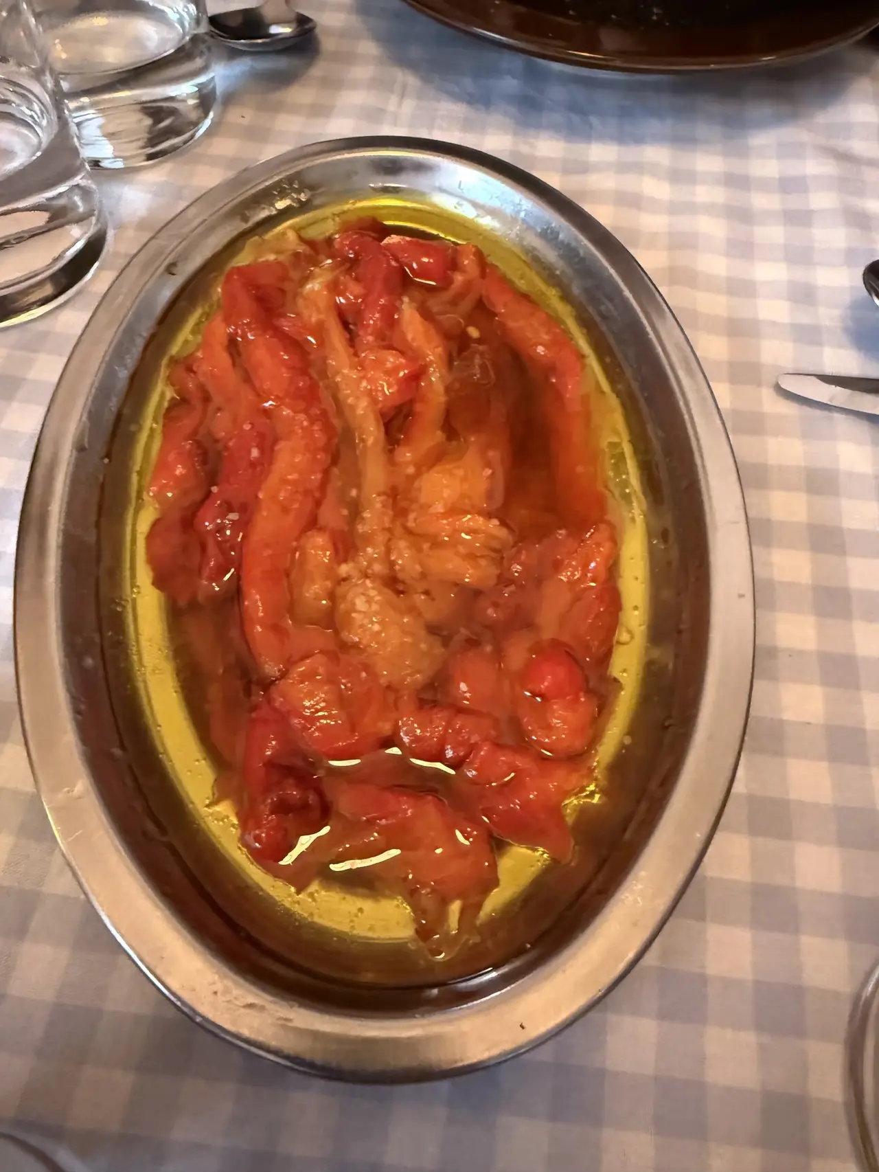 Roasted red peppers with garlic in olive oil on a metal dish