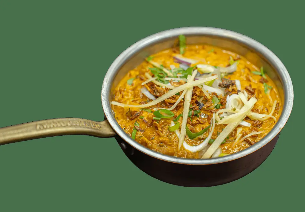 Creamy orange curry topped with julienned ginger, onion, and herbs served in a small copper-handled pan, Rasoi (Rasoi BCN)
