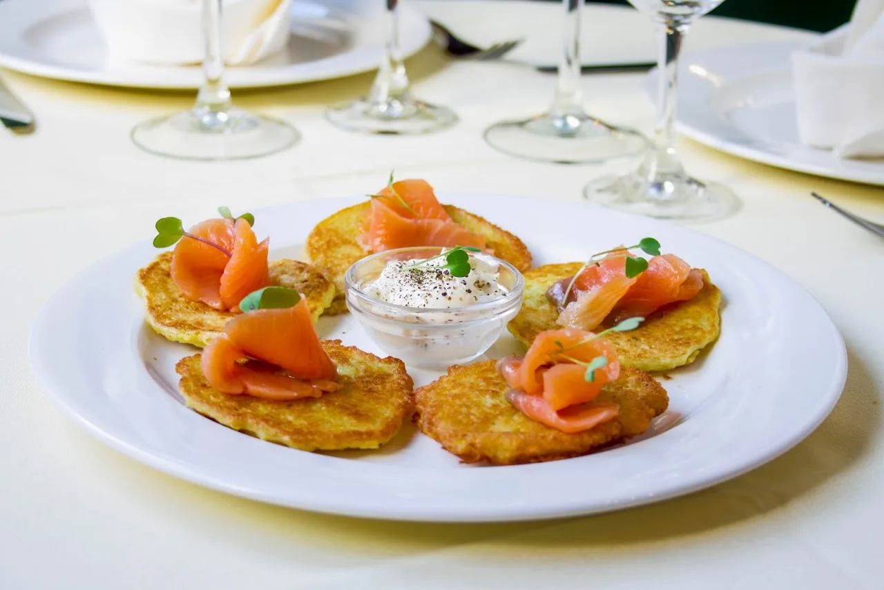 A plate of potato pancakes topped with smoked salmon, served with a dollop of sour cream