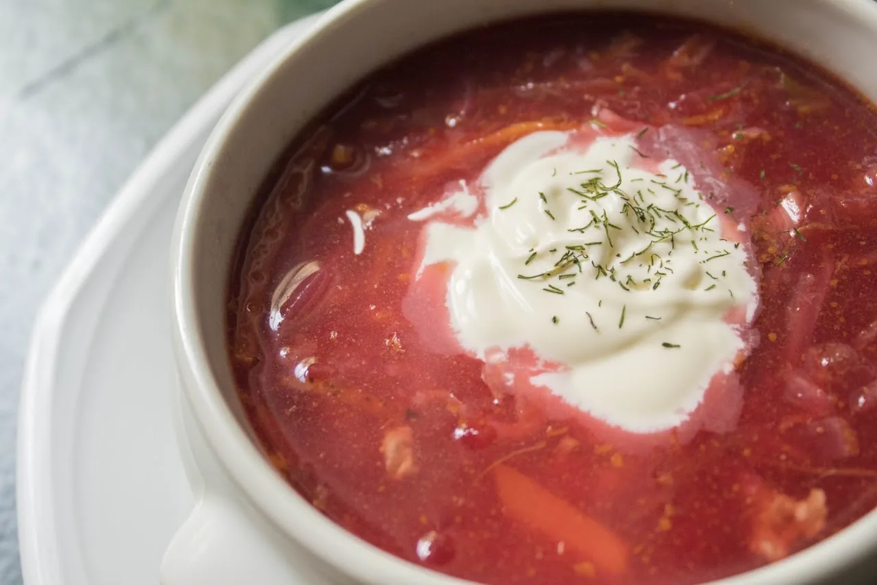 A bowl of borscht beet soup topped with a dollop of sour cream and dill