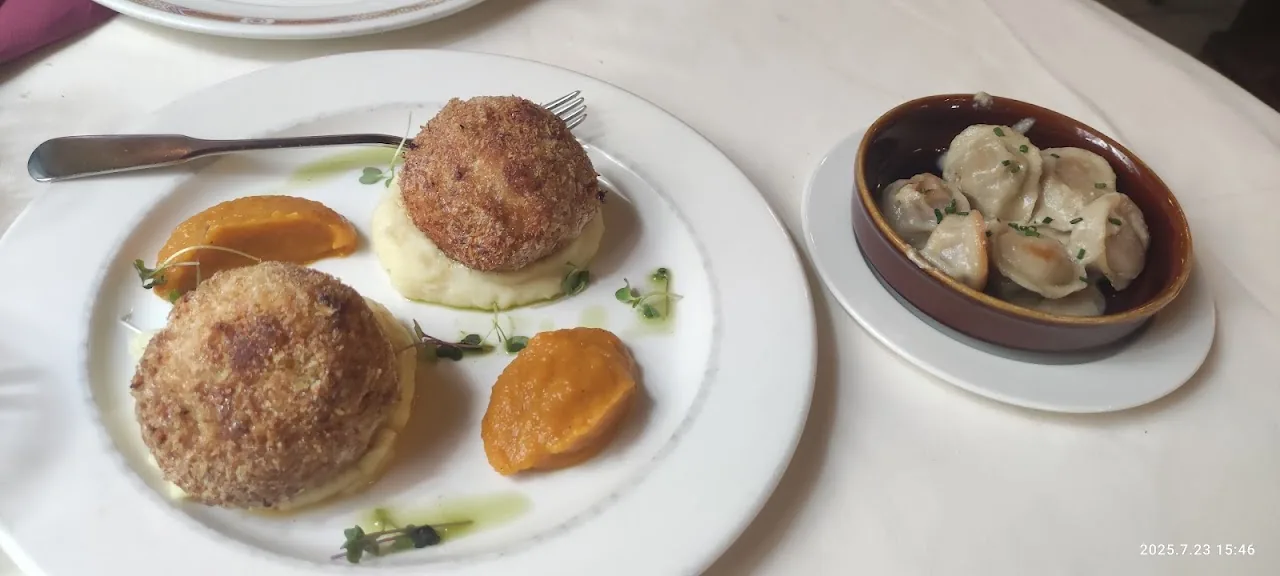 A plate with a meatball, a breaded croquette, and a side of mushrooms in a small dish
