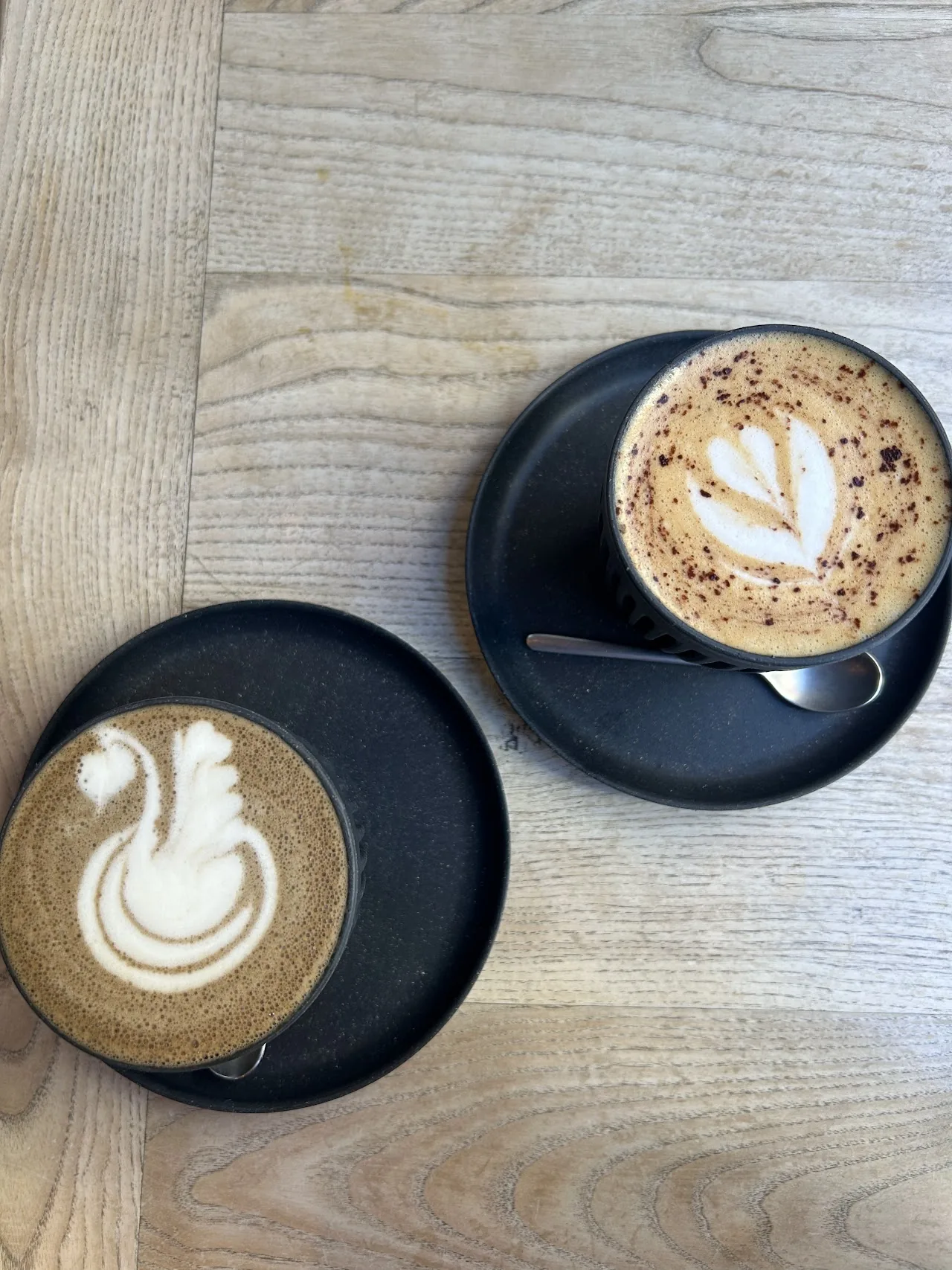 Two coffees in latte-art cups on a wooden table