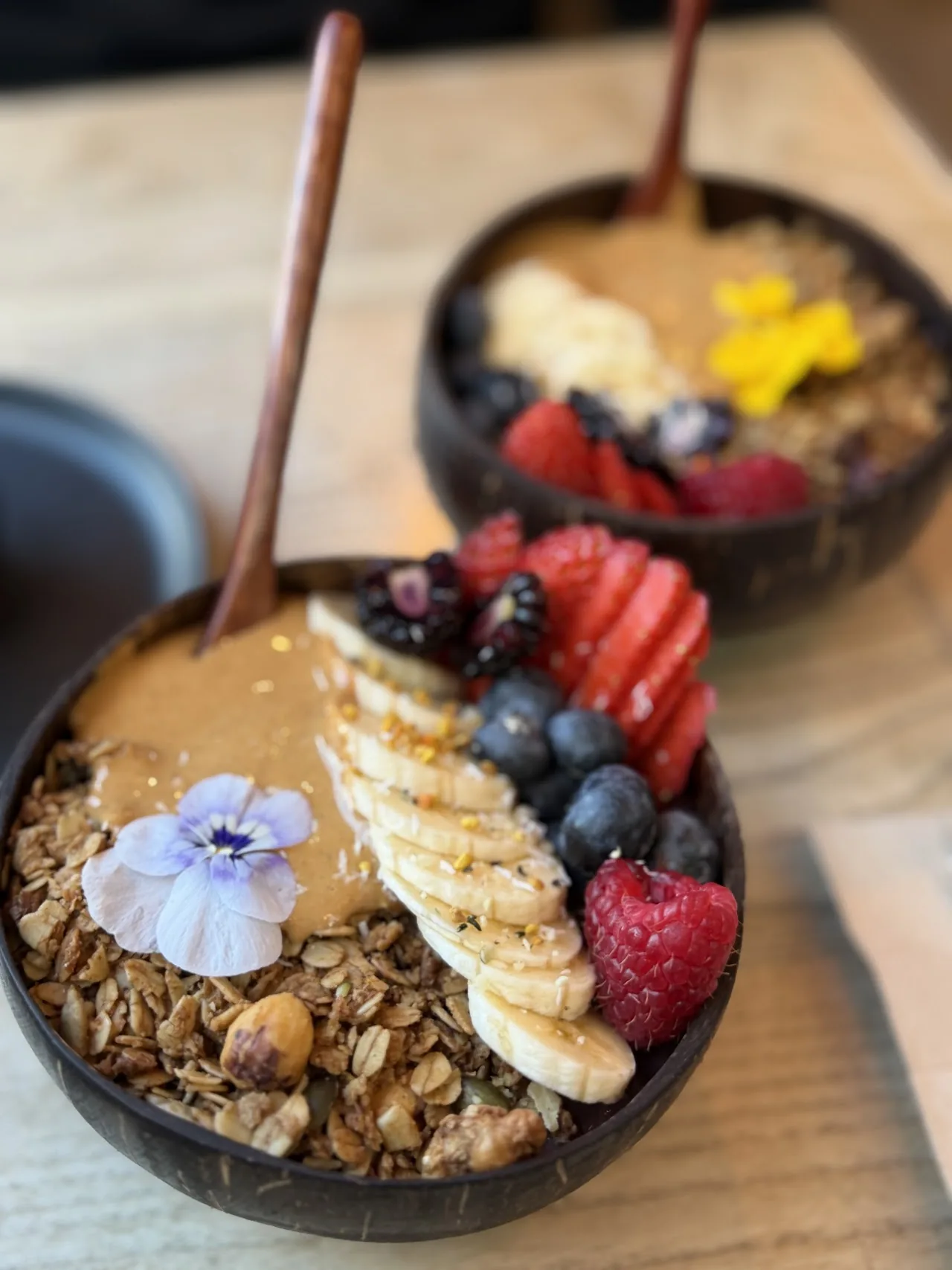 A granola bowl topped with sliced banana, berries, and a swirl of nut butter