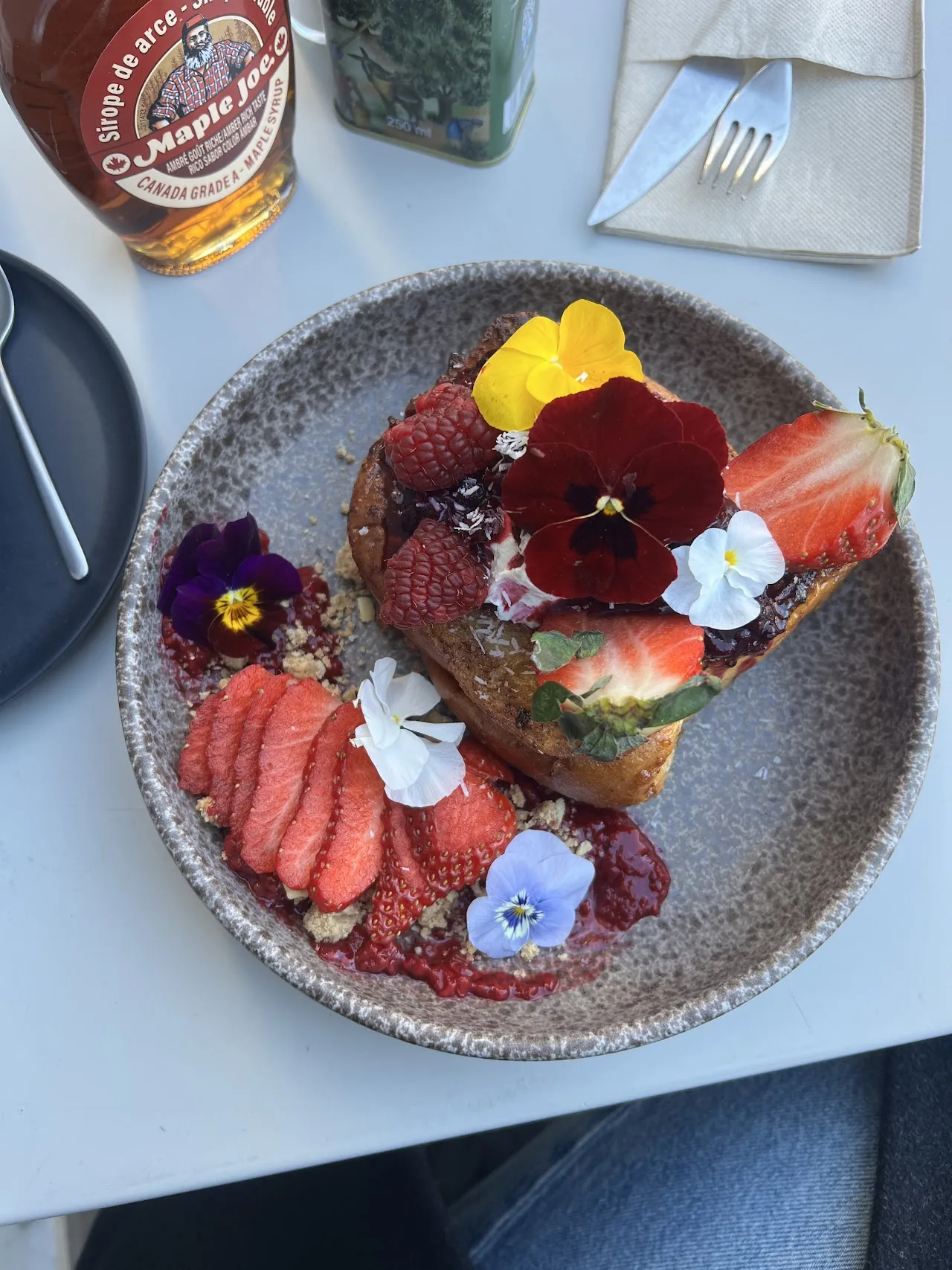 A slice of toast topped with strawberries, mixed berries, and edible flowers