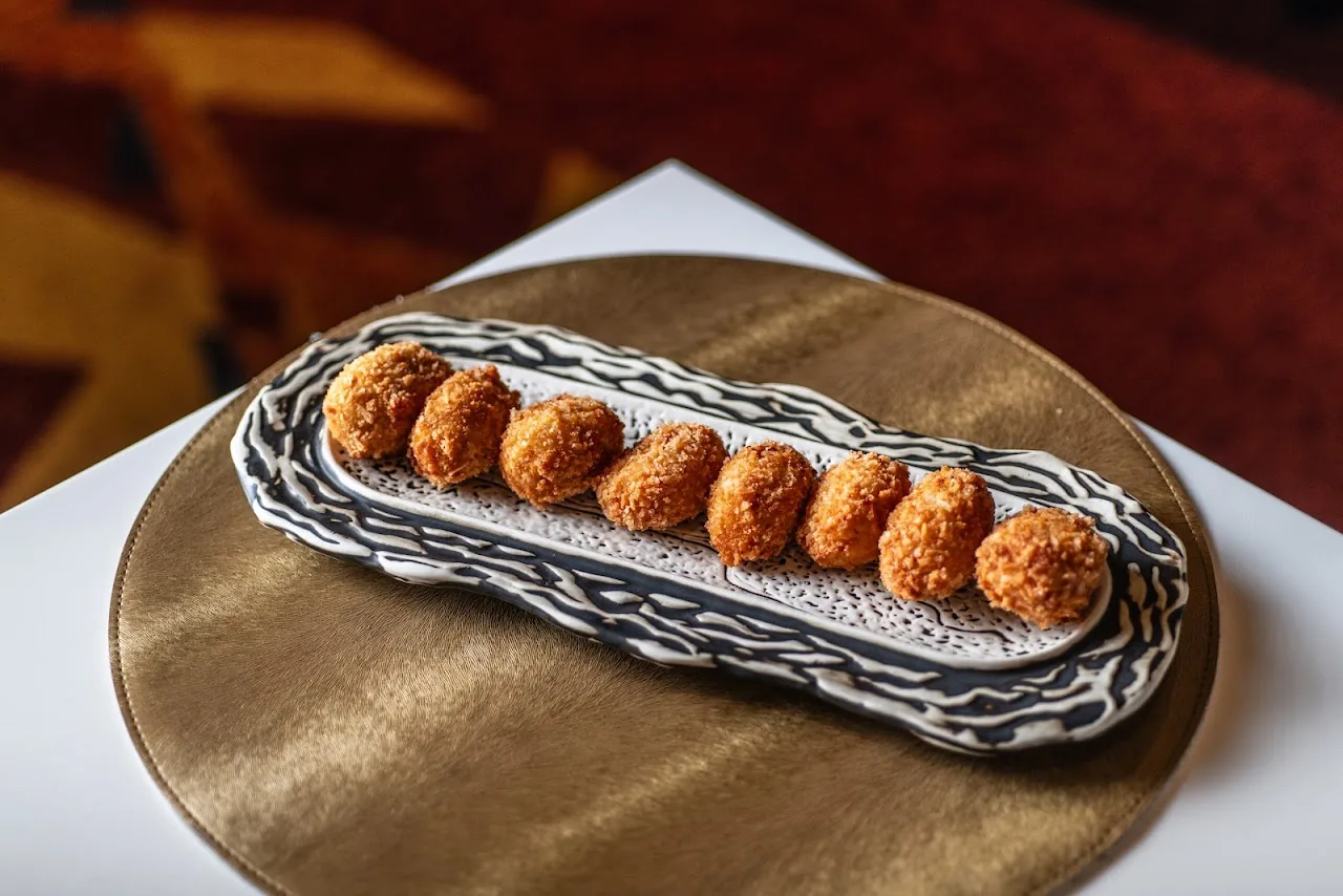 A row of golden fried croquettes on a striped serving plate