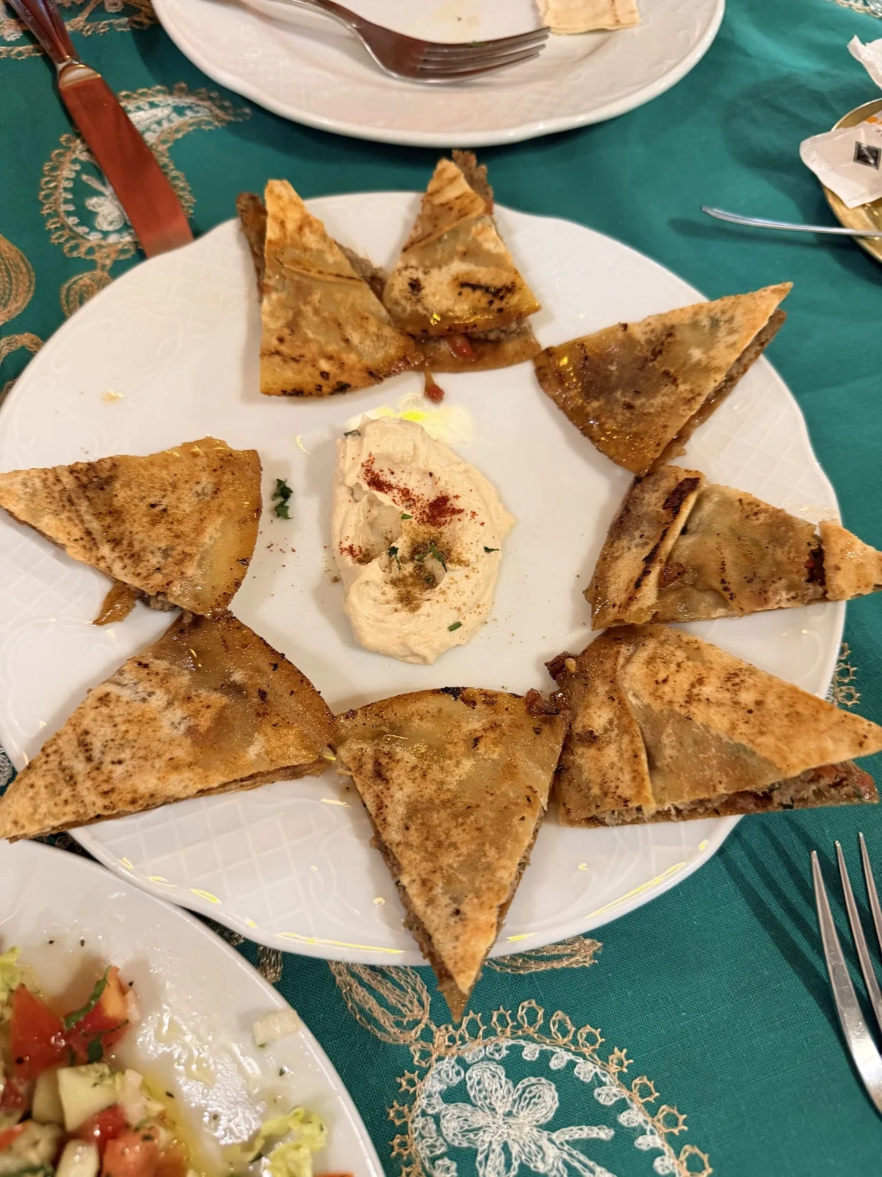 Pita bread triangles arranged in a star shape around a dip, with a tomato salad