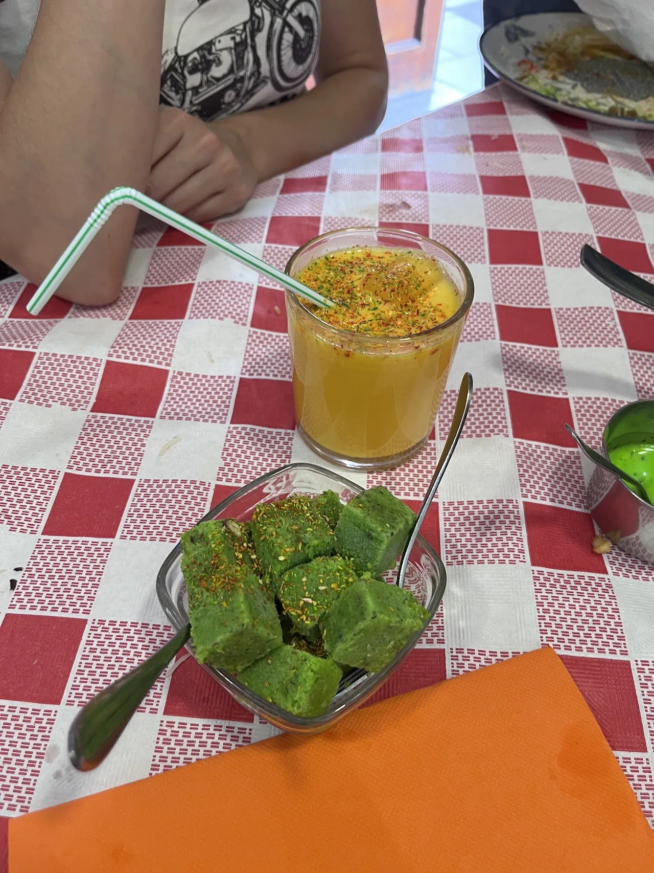 A mango lassi drink next to a small side dish