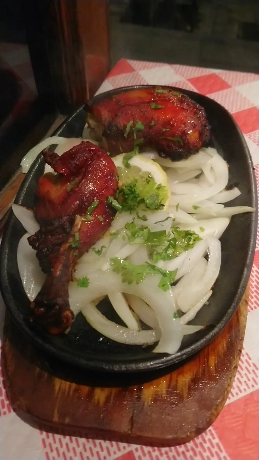 Sizzling tandoori chicken on a hot skillet with onions