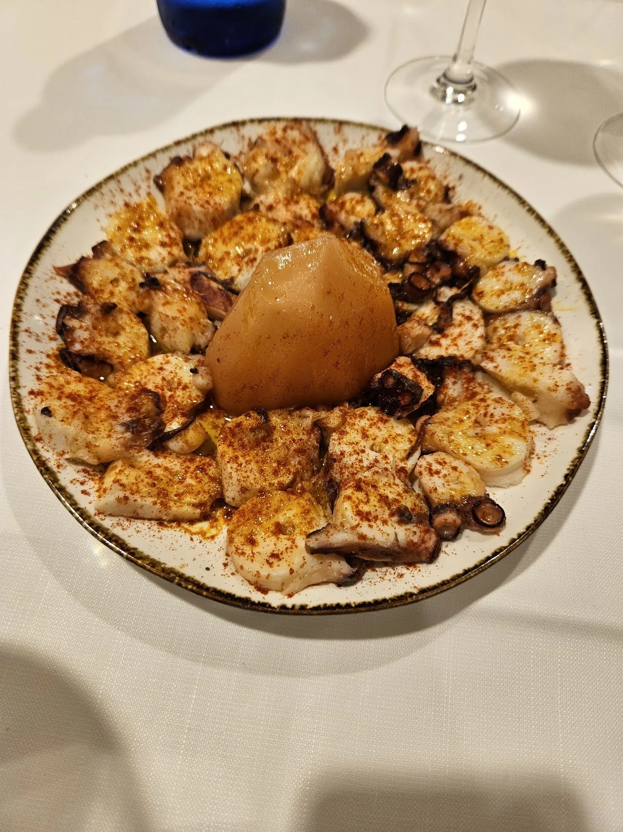 Pieces of octopus on a round plate with a boiled potato