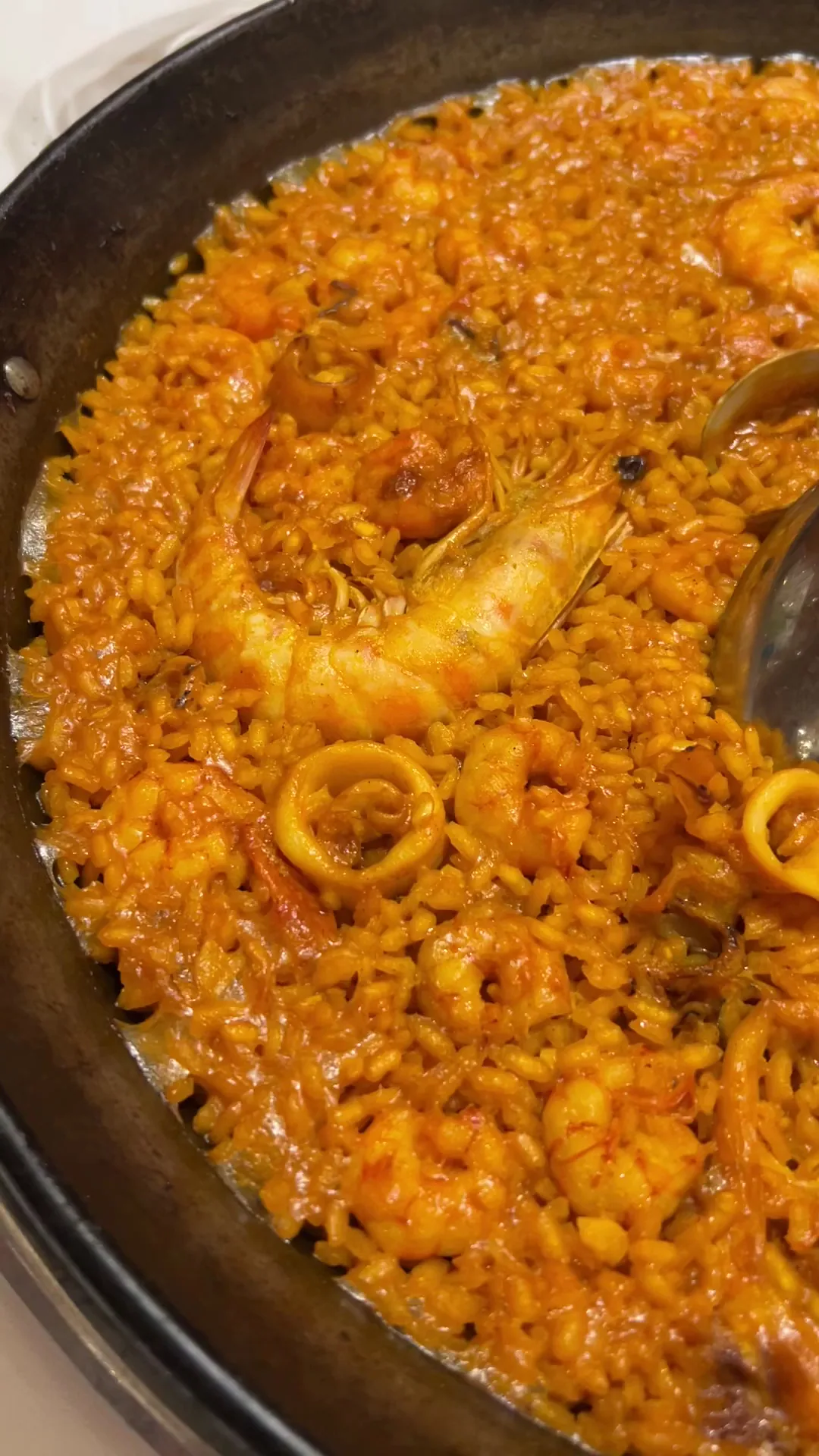 A pan of seafood paella with shrimp and squid rings, viewed close-up