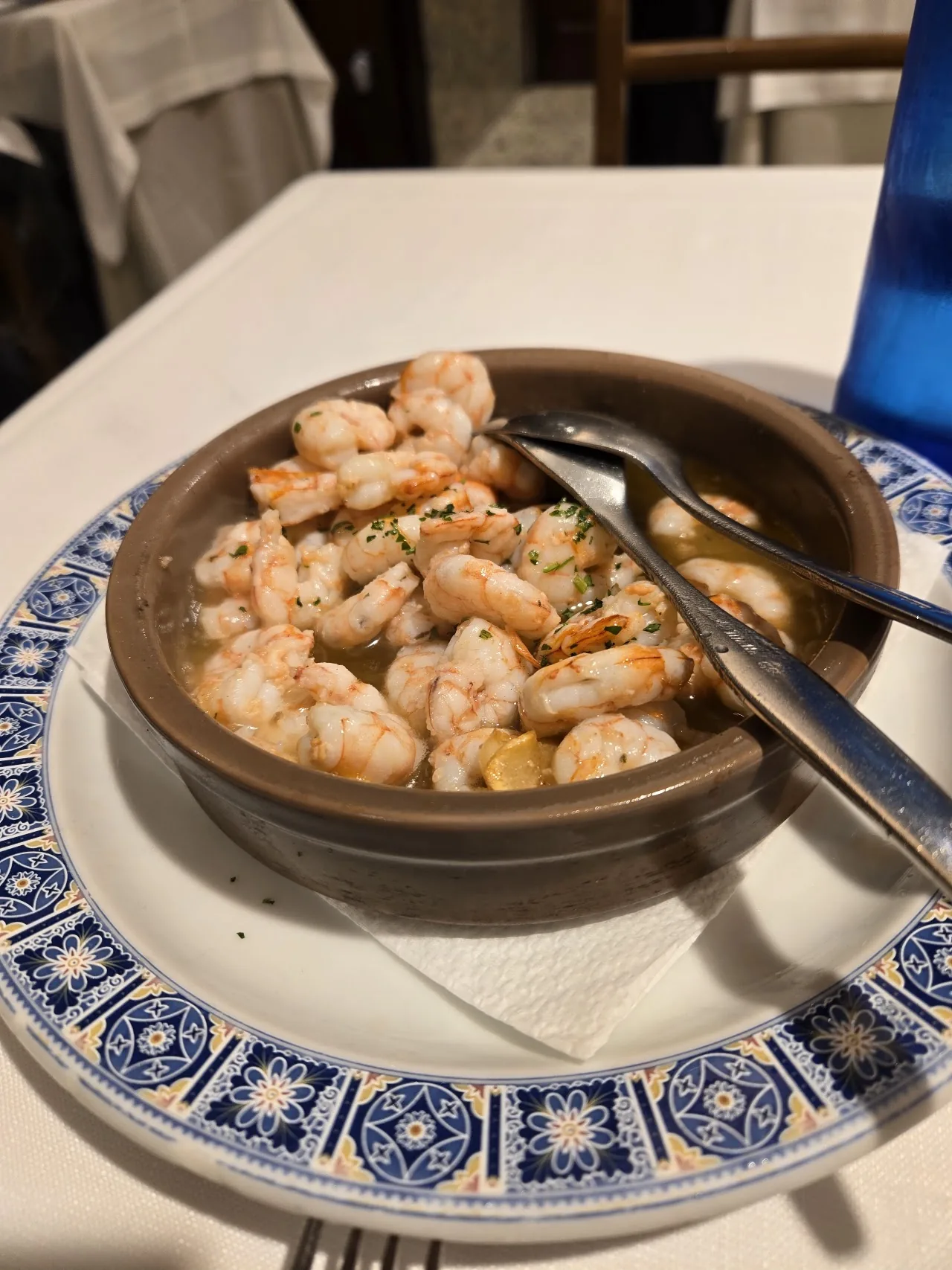 A clay dish of shrimp cooked in garlic and olive oil