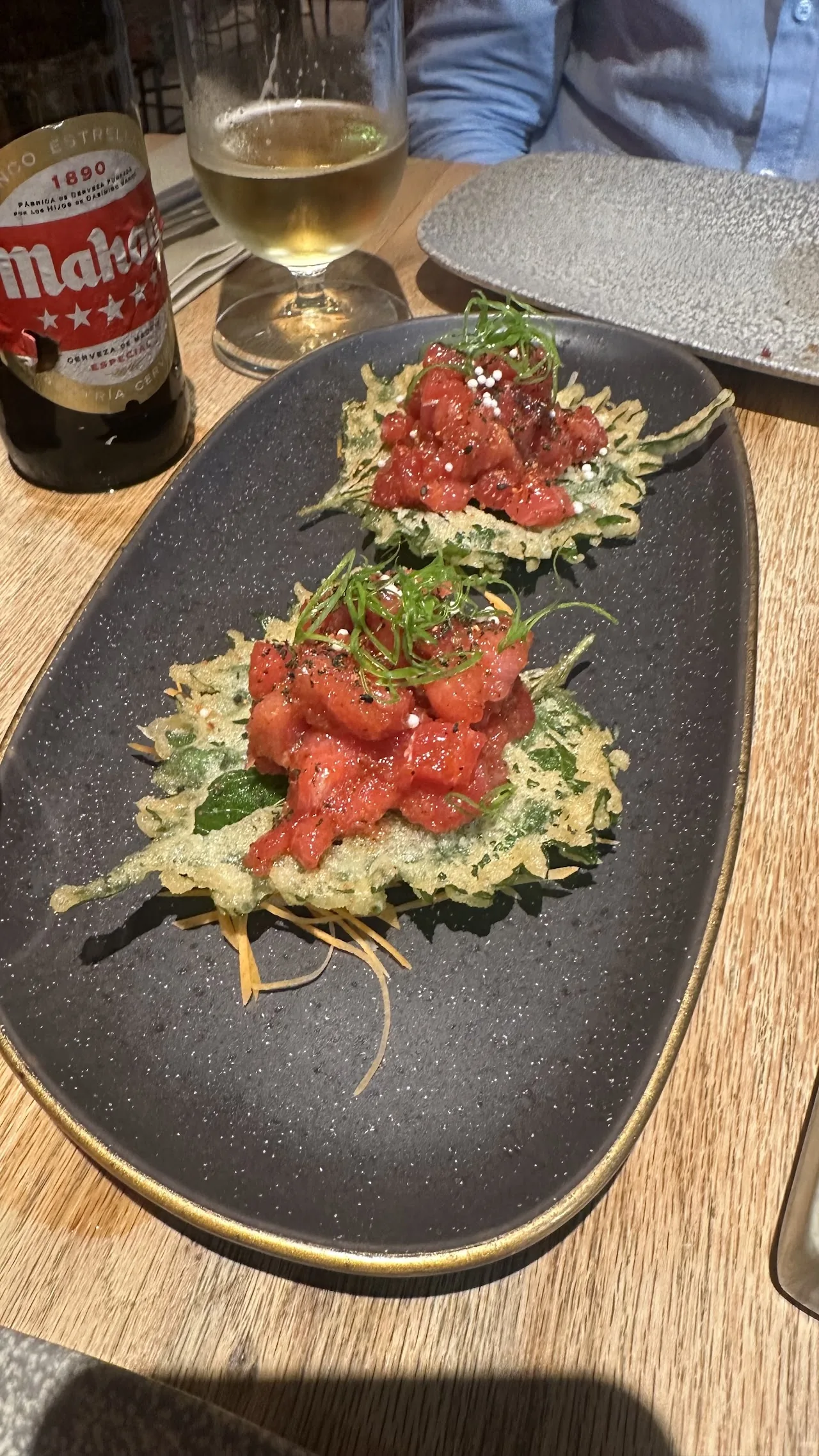 Tuna tartare tostas topped with greens on a black plate