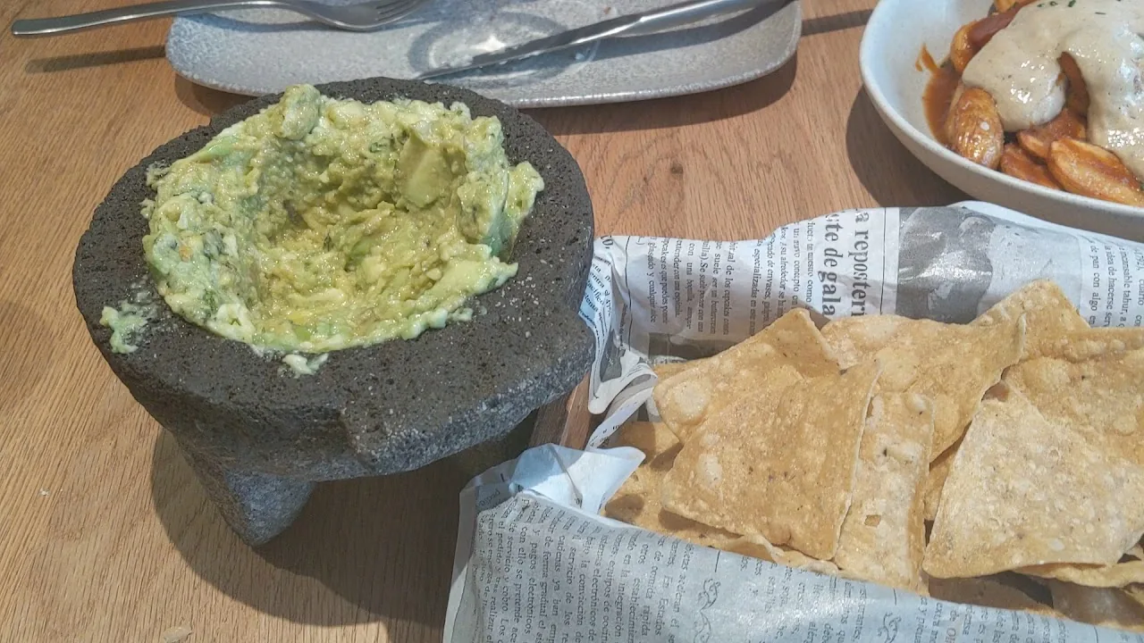 A stone mortar of guacamole served with tortilla chips