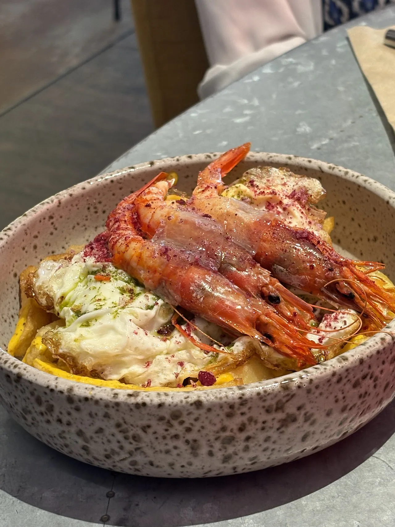 A bowl of grilled prawns over rice with sauce
