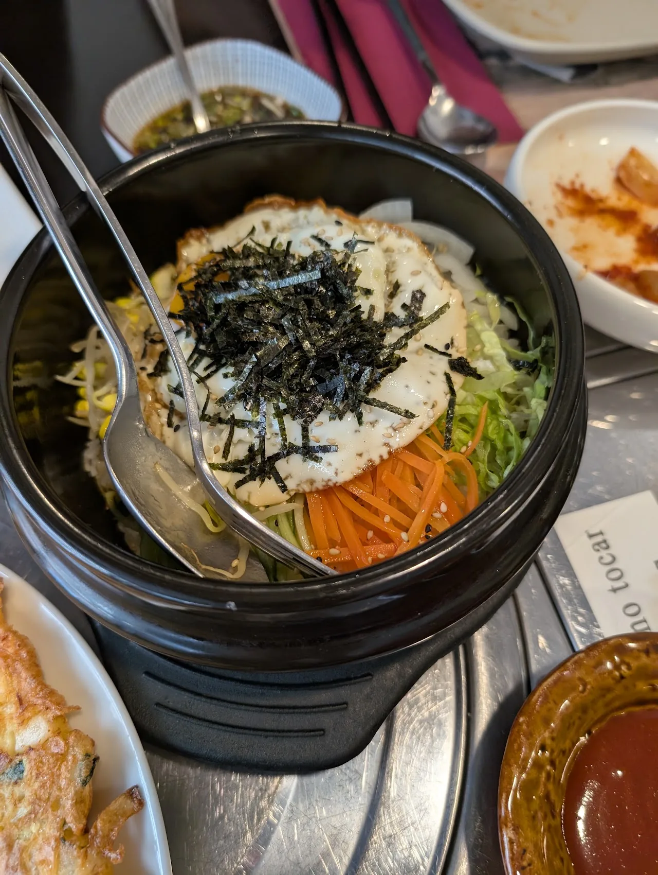 A stone bowl of bibimbap topped with rice and seaweed