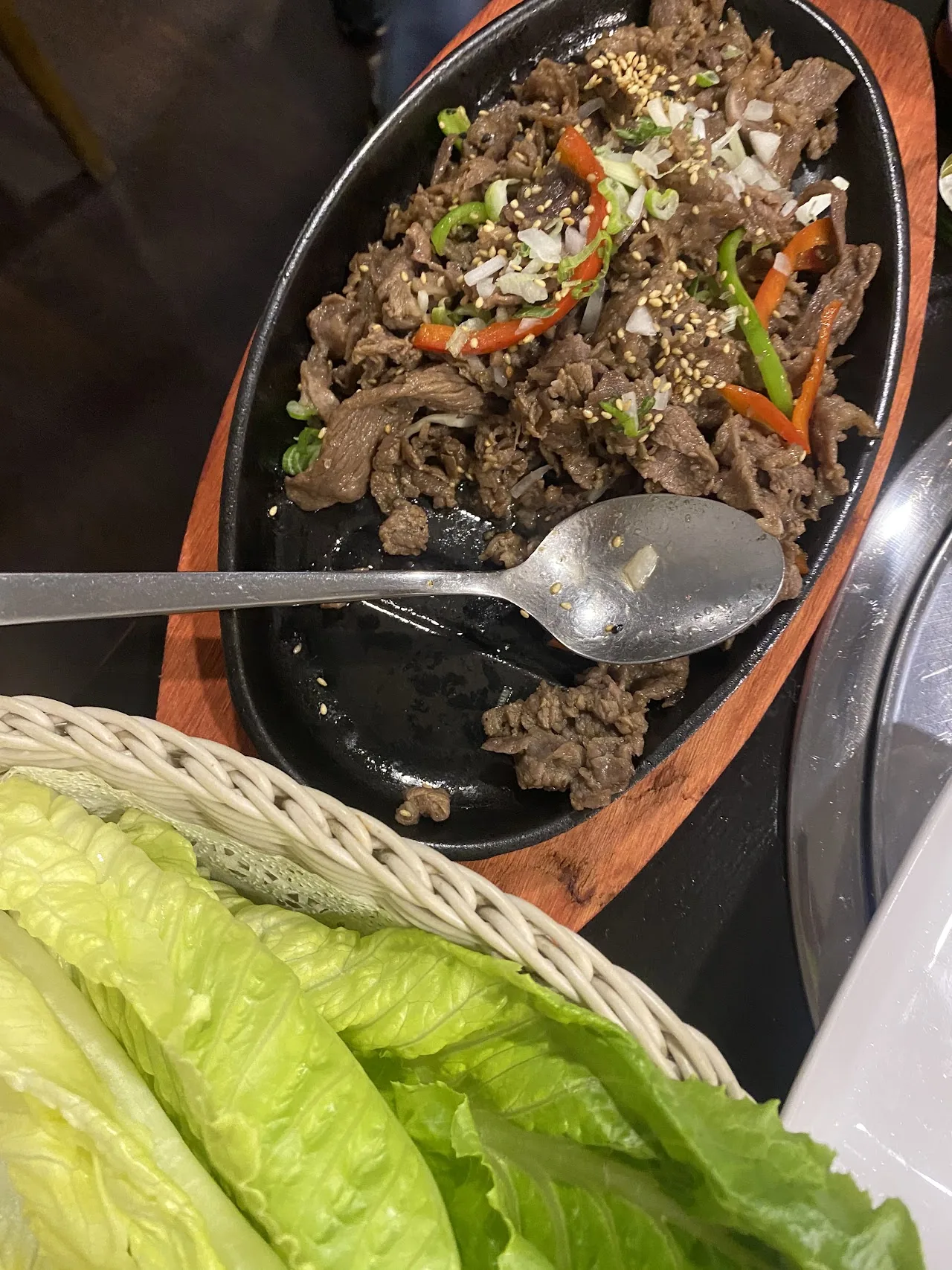 A sizzling plate of beef and vegetable stir-fry with lettuce wraps
