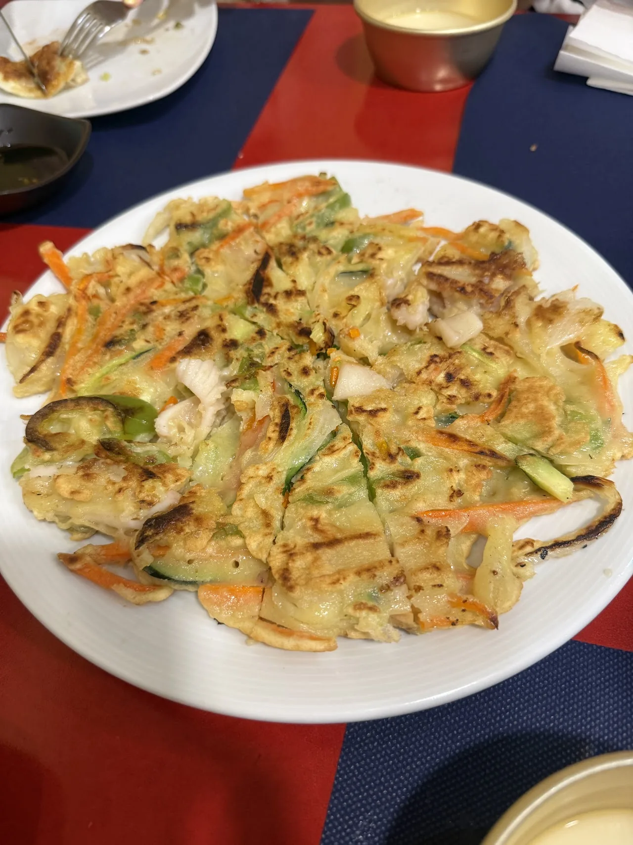 A seafood and vegetable pancake on a white plate