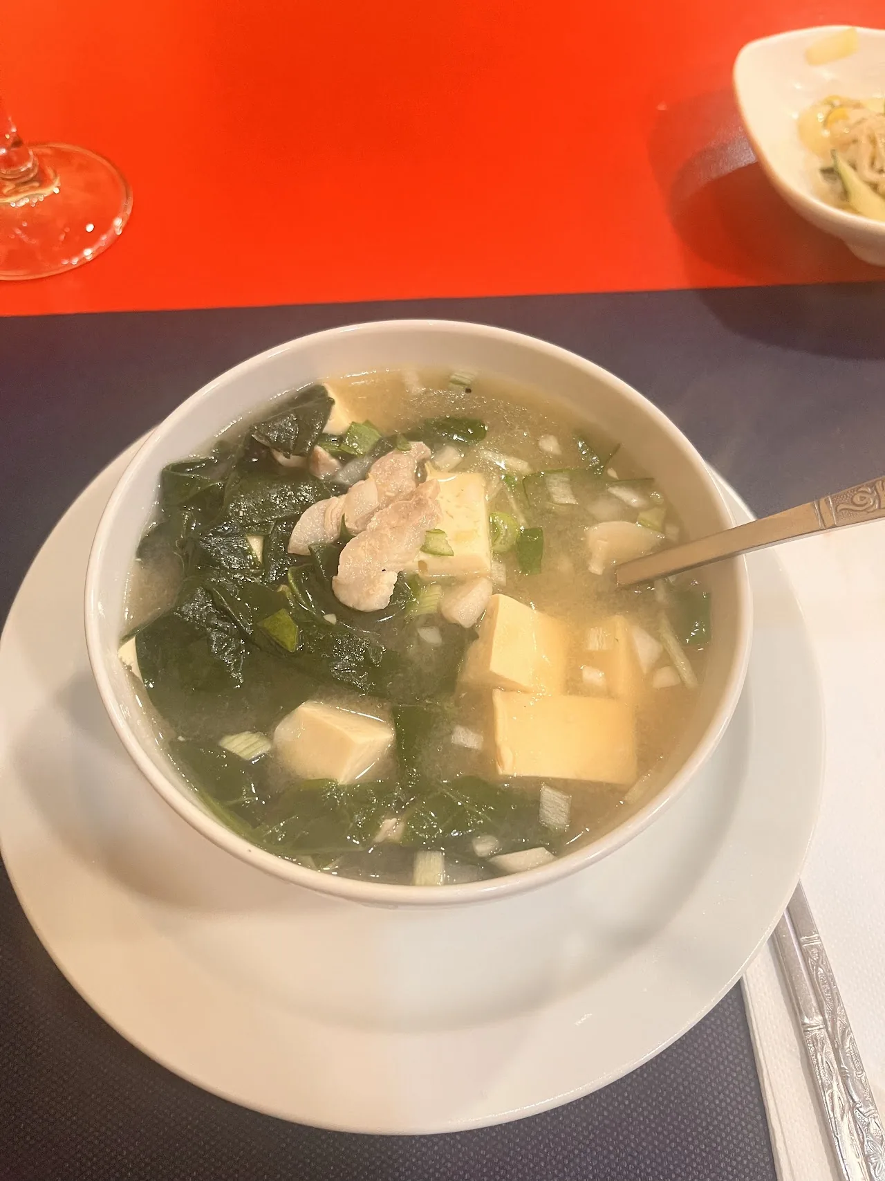 A bowl of soup with tofu and leafy greens