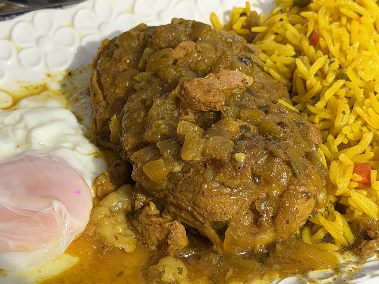 A stew with rice, meat and a fried egg on the side